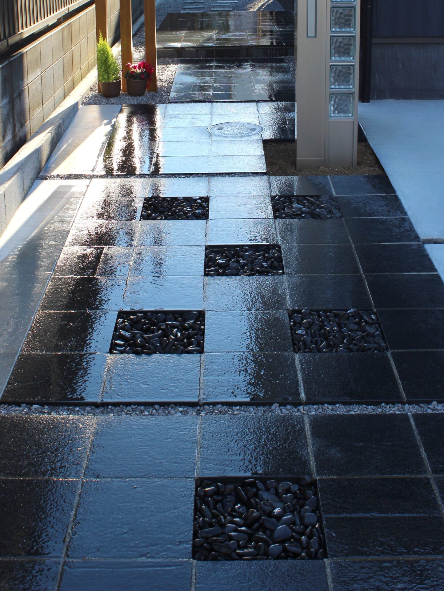 鴻巣市　自然石と黒い玉石のアプローチが建物と調和するオープン外構のアプローチ、雨の日バージョン