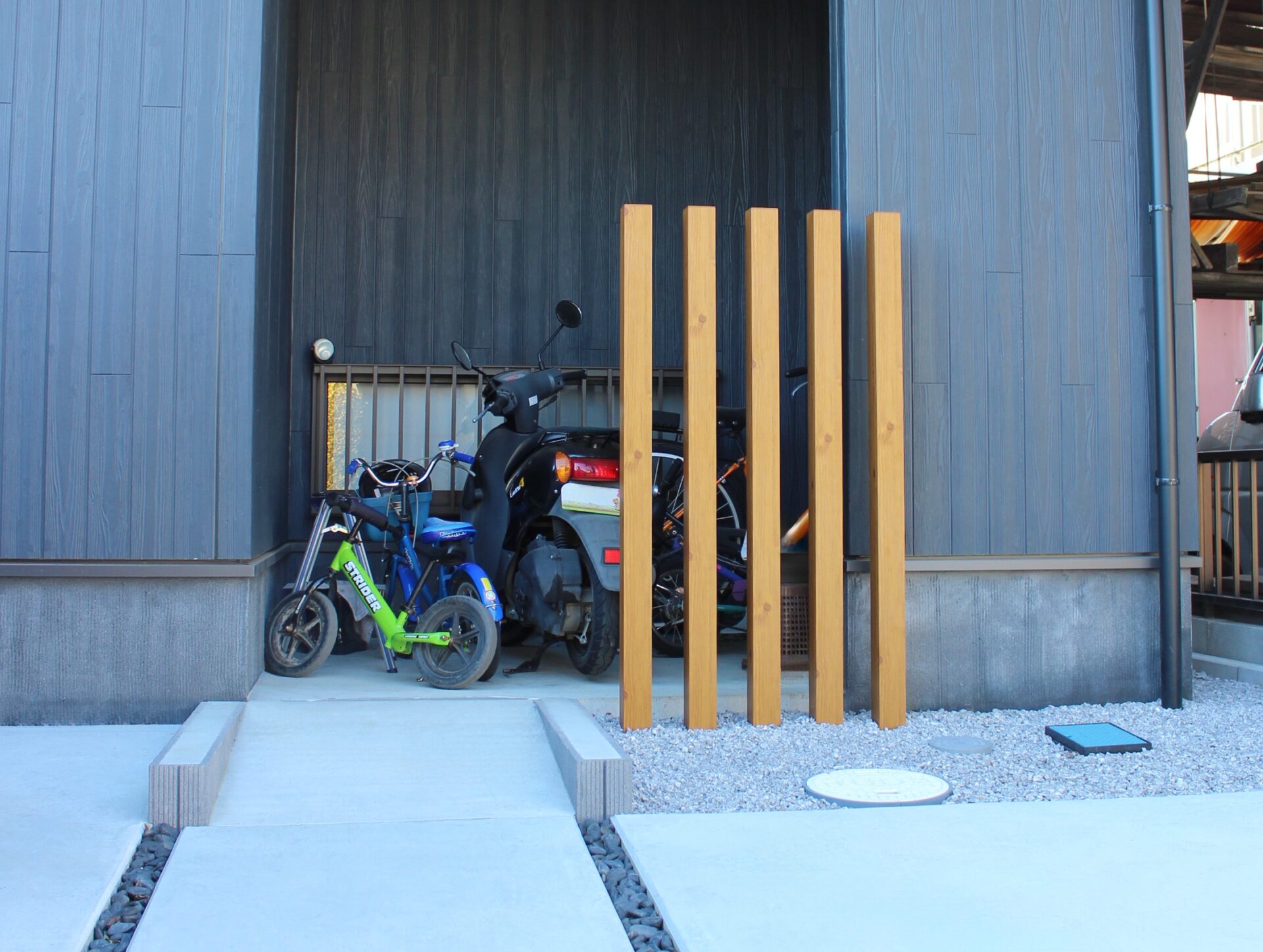 鴻巣市　自然石と黒い玉石のアプローチが建物と調和するオープン外構のバイク、自転車保管場所